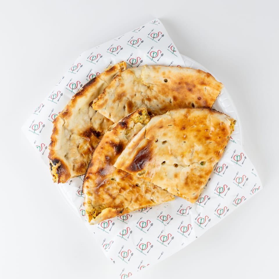 Golden-brown stuffed flatbreads arranged on a branded paper-lined plate.