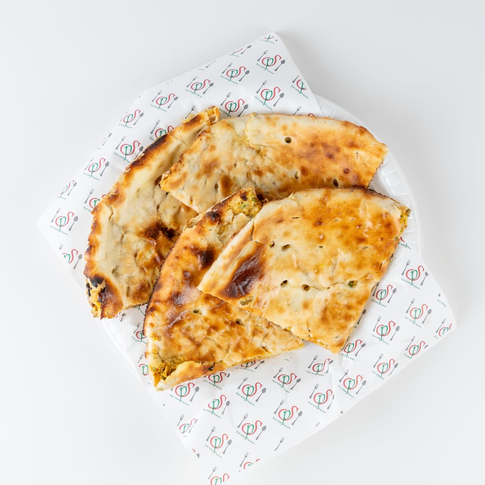 Golden-brown stuffed flatbreads cut into pieces and arranged on a branded paper-lined plate.
