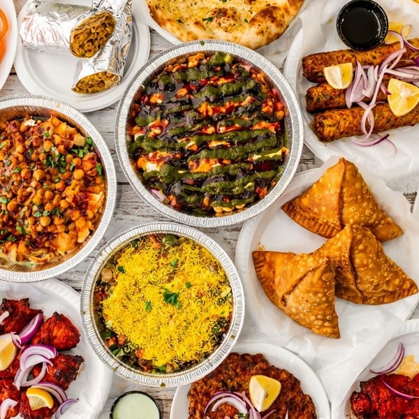 A vibrant overhead spread of various Indian dishes including biryani, samosas, kebabs, and desserts.